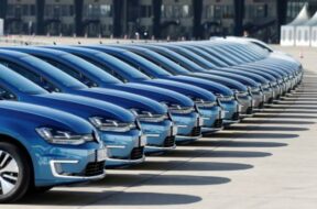 People walk pasta row of Volkswagen e-Golf cars during the company’s annual news conference in Berlin