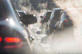 Blurred silhouettes of cars surrounded by steam from the exhaust