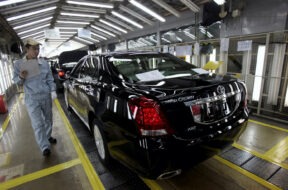 FILE PHOTO: An employee checks on newly produced cars at a Toyota factory in Tianjin