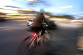 Radfahrer radelt auf einer Straße in der Innenstadt von Heidelberg und wird von einem Auto überholt, Baden Württemberg,
