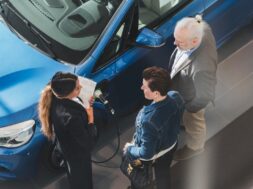 High angle view of saleswoman talking to customers at car showroom