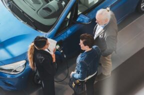 High angle view of saleswoman talking to customers at car showroom