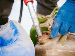 adult man fills a car with petrol at a fuel station in the winter. refueling nozzle man holding in his hand, pouring the