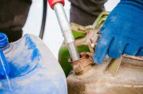 adult man fills a car with petrol at a fuel station in the winter. refueling nozzle man holding in his hand, pouring the
