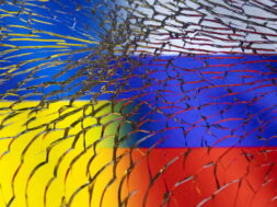 Illustration shows Ukraine and Russian flags through broken glass